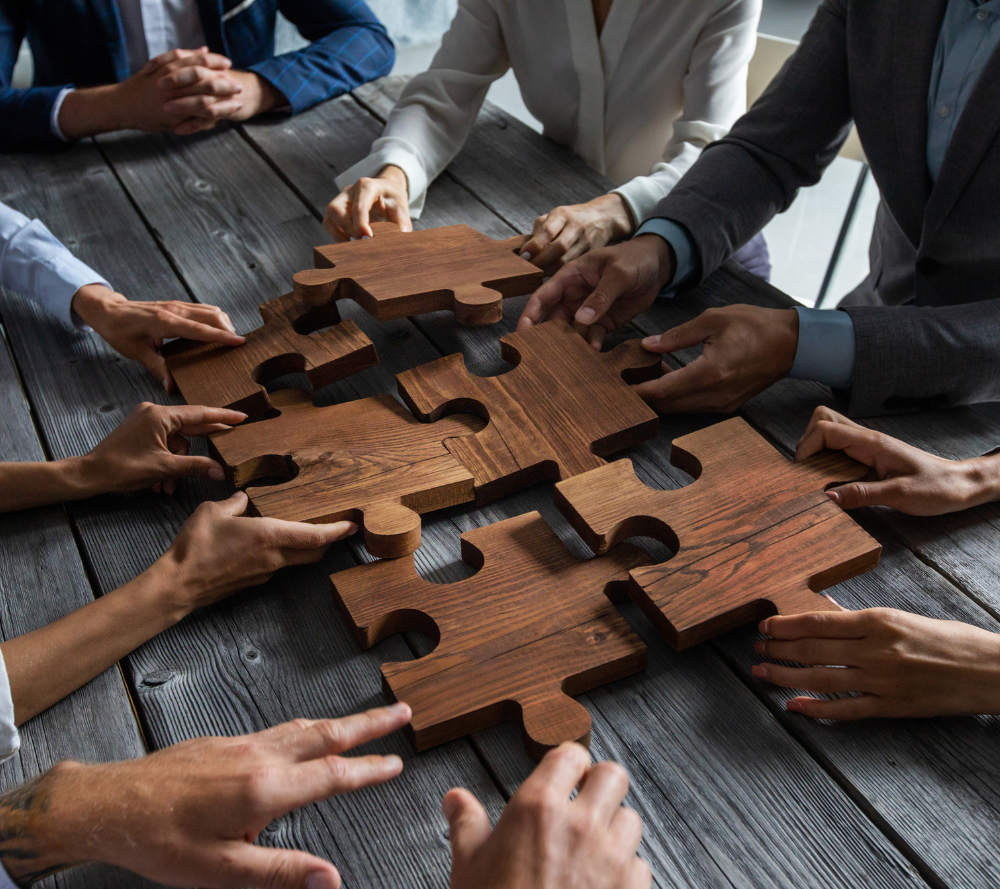 Suited individuals putting a puzzle together on a table.